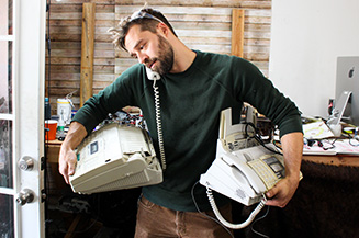 Josh A. Weston holds fax machines used for his art work.